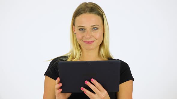 A Young Beautiful Woman Smiles at the Camera and Works on a Tablet - White Screen Studio