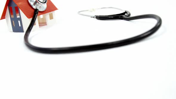 Close-up of house model and stethoscope against white background