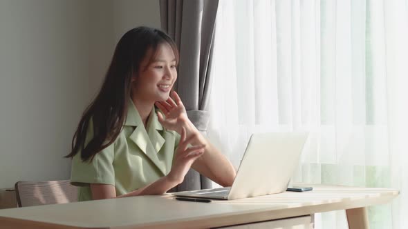 Happy young asian woman using laptop to video call or facetime to talk customer or friend