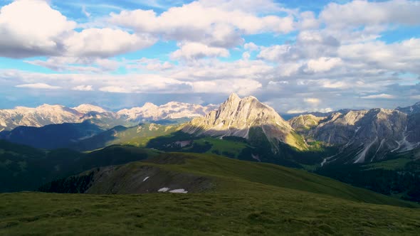 Aerial view flying across lush grassy meadow overlooking spectacular rugged Dolomites landscape