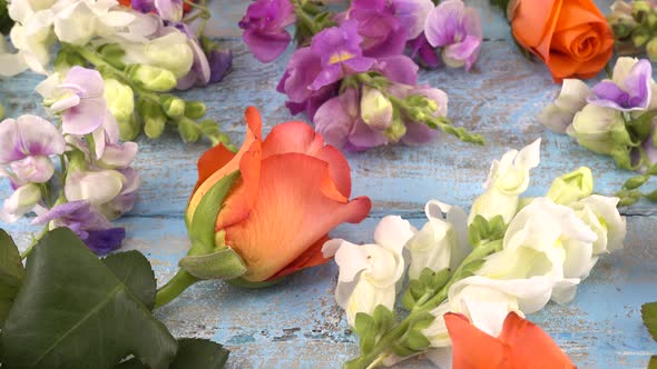 Colorful summer garden flowers: dragon flowers, roses, sweet pea on the vintage wooden