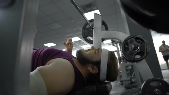 Injured Man in Gym Feeling Sharp Pain in Arm, Lifting Barbell on Bench Press