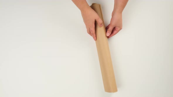 woman holding roll of brown parchment paper on white background