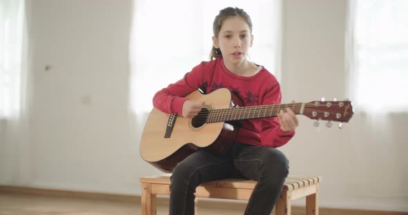 young girl playing guitar and singing