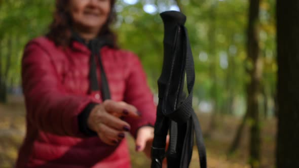 Closeup Poles for Nordic Walking with Blurred Unrecognizable Mature Woman Taking Sport Equipment