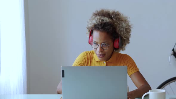 African American Woman with Headphones Working Cheerful at Home with a Laptop