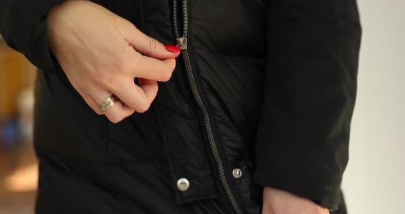 Woman's hand fasten the zipper on a black jacket, ready to walk