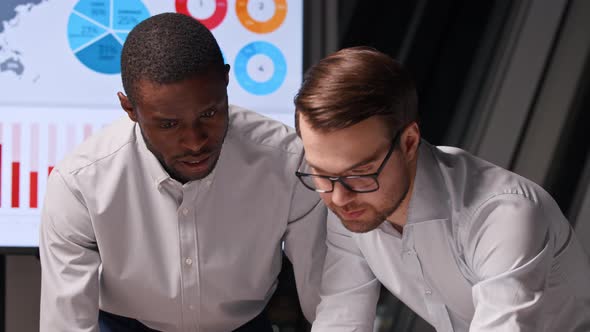 Two young colleagues working on the background of graphs and diagrams