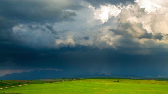 Dark thunderclouds over lighted spring fields/