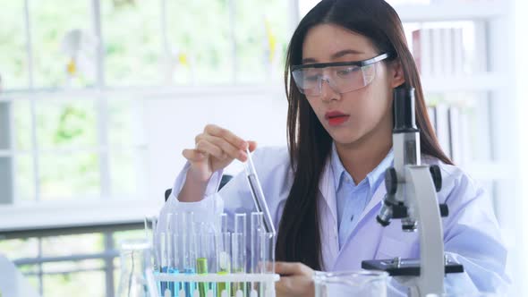 Asian Medical Researcher Working in Pharmacy Laboratory While Mixing Chemical in Flask with Tube