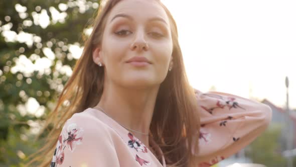 Woman with Loose Fair Hair in Pink Dress Smiles and Poses