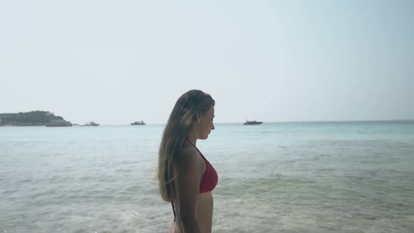 Girl in Red Bikini Walks Along Tropical Beach Against Ocean