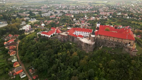 Aerial view of medieval castle on mountain in small european city at cloudy autumn day