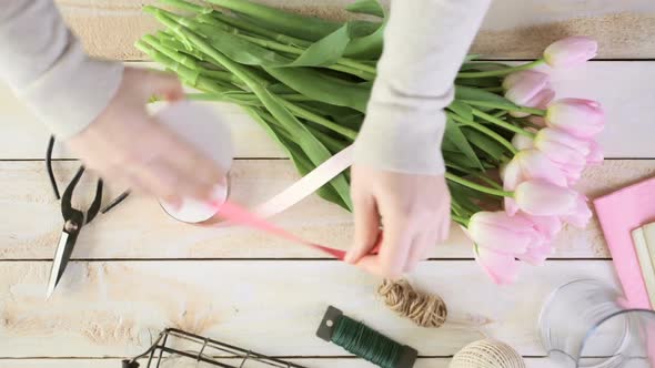 Time-lapse. Step by step. Florist wrapping pink tulips in bouquet