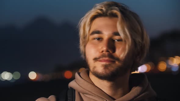 Blonde Man in Beige Hoodie on the Night Beach