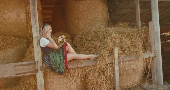 Blonde with Bouquet of Flowers Posing with Hair and Flirting on a Hayloft