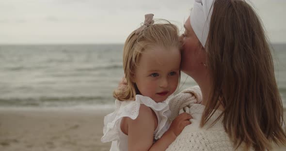 Mother and Baby Daughter Spend Time on the Beach Together Embracing