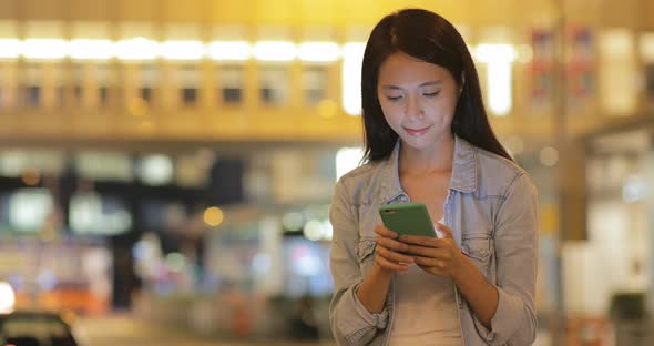 Woman using cellphone at night in Hong Kong 