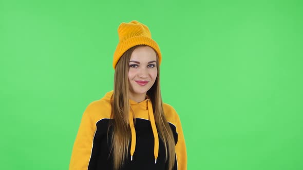 Portrait of Modern Girl in Yellow Hat Is Coquettishly Smiling and Showing Gesture Come Here. Green