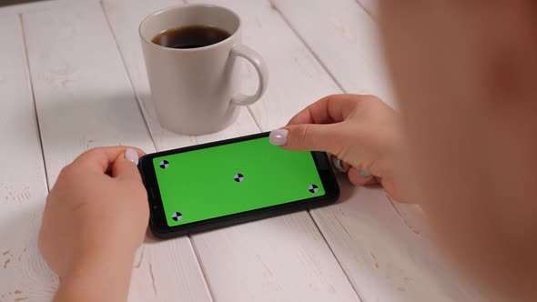 Closeup of a Woman Holding a Phone with a Chroma Key and Drinking Coffee