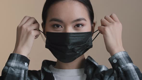 Portrait Female Masked Face Asian Woman Taking Off Medical Mask Smiles Indoors Looking at Camera