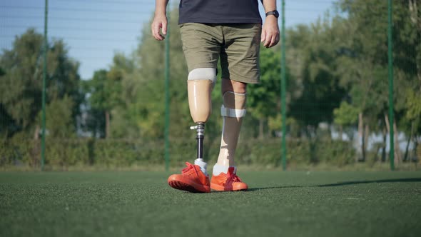 Front View Unrecognizable Amputee with Artificial Legs Playing Soccer in Slow Motion on Sunny Summer