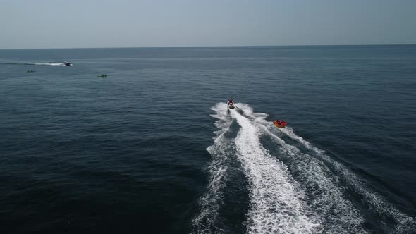 Happy People are Going to Swim on an Air Mattress Behind a Jet Ski