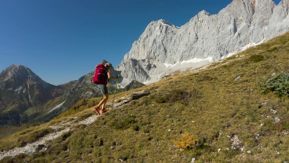 4K Aerial Drone Footage Following Woman Hiking in Mountains at Sunshine