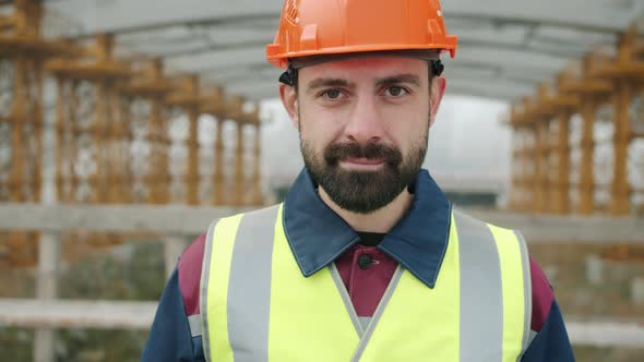 Cheerful Construction Professional Wearing Safety Helmet and Vest Smiling in Building Area
