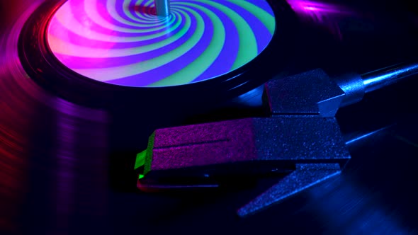 Top View of Turntable Needle on Vinyl Record Close Up Illuminated with Bright Neon Lights
