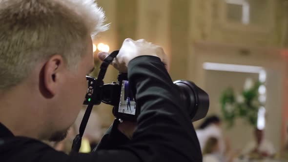 Man Photographer Takes Pictures in a Restaurant Party at Wedding Event