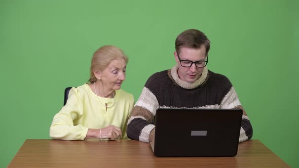 Happy Senior Businesswoman and Young Handsome Man Using Laptop Together