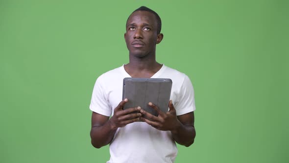 Young African Man Thinking While Using Digital Tablet