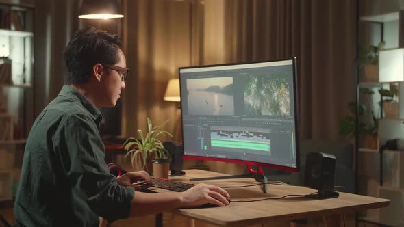Asian Male Video Editor Works With Footage And Sound On His Personal Computer