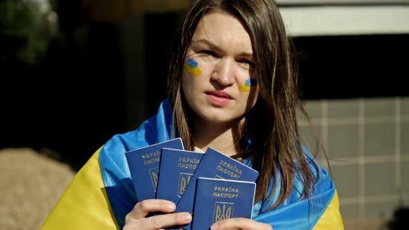 Woman Covered with the Flag of Ukraine with Ukrainian Passports in Her Hands