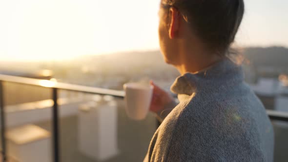 Woman Starts Her Day with a Cup of Tea or Coffee on the Balcony at Dawn Slow Motion