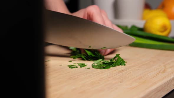 Chopping fresh parsley on wooden board slow motion.