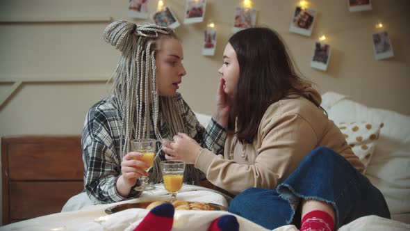 Young Lesbian Women Having a Breakfast in Bed  Drinking Juice and Playing with Hair