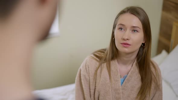 Portrait of Anxious Beautiful Ill Woman Talking with Unrecognizable Doctor in Hospital Ward