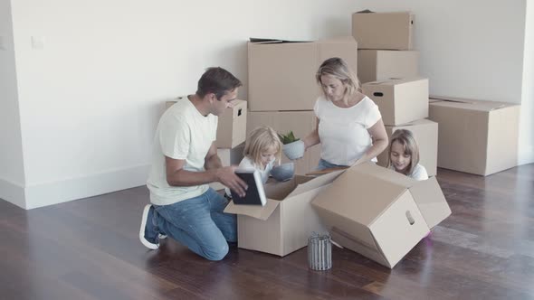 Cheerful Family with Kids Unpacking Things in New Apartment