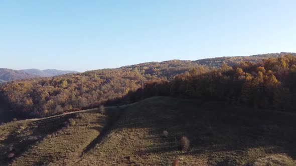 Aerial view of country hills at sunset in autumn season. Beautiful rural scene with dead nature, ear