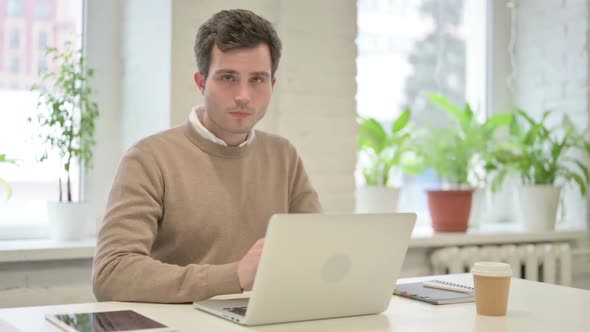 Man Shaking Head As No Sign While Using Laptop in Office