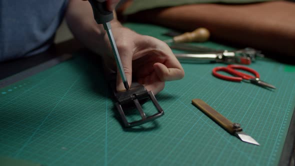 Artisan Completing Repair of Leather Belt Laying It on Table Indoors
