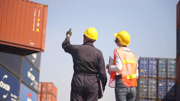 Engineer and foreman team in hardhat and safety vest control loading containers box from cargo