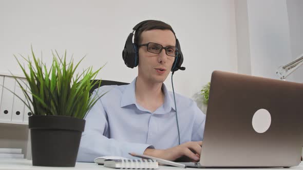 Friendly Professional Call Center Agent Wear Wireless Headset Making Conference Video Call on Laptop