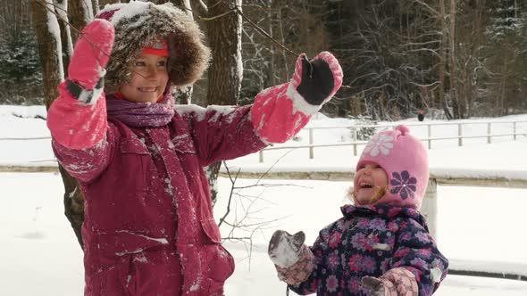 Lovely Kids Throwing A Handful Of Snow Up In The Air.