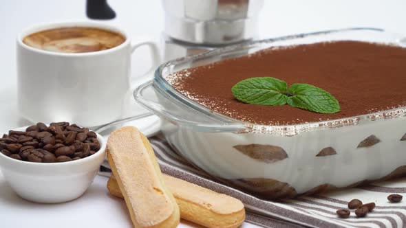 Tiramisu Dessert in Glass Baking Dish, Savoiardi Cookies, Coffee Maker and Cup of Fresh Espresso