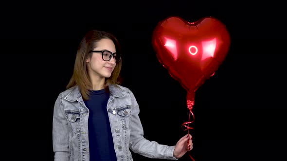 A Young Woman Kisses an Inflatable Balloon in the Form of a Heart, Woman with a Balloon Filled with