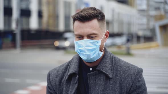 Facial portrait of a man in protective mask. Young handsome man on blur city background