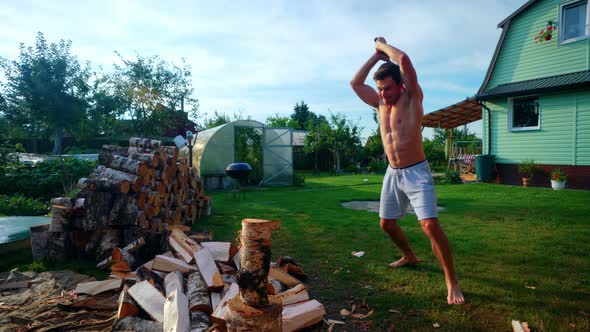 Slow Motion Shot Of A Man Forcefully Breaking A Log Using An Axe During Summer In Lithuania, Europe